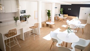 Une cuisine moderne avec des armoires blanches, un four encastré et des luminaires suspendus.