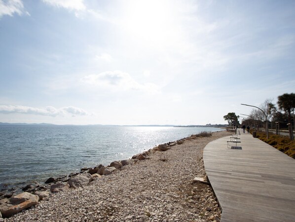 Un paseo marítimo con playa de guijarros y una pasarela de madera.