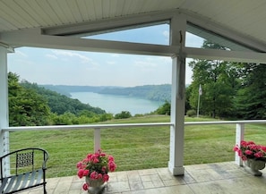 A covered outdoor area with a view of a lake and hills.