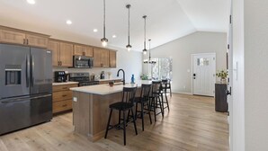 A modern kitchen with wooden cabinets, stainless steel appliances, and a central island with bar stools.