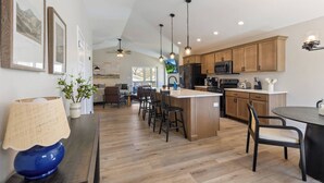 A modern kitchen with wooden cabinets, a central island, and pendant lighting.