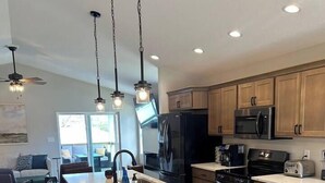 A modern kitchen with a central island, stainless steel appliances, and wooden cabinets.