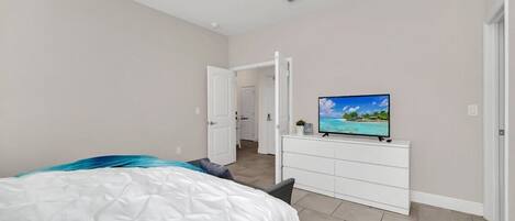 A bedroom with a bed, a TV on a dresser, and a ceiling fan.