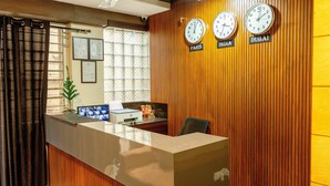 A reception desk with clocks labeled Paris, India, and Dubai, a computer, and framed documents on the wall. - Hotel Rize Inn (Bengaluru)