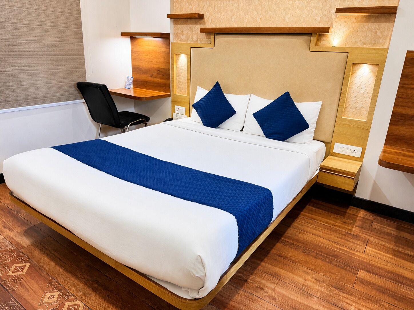 A hotel room with a large bed, a desk, and a chair.