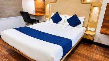 A hotel room with a large bed, a desk, and a chair.
