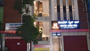 A multi-story hotel with a modern design, featuring balconies and a prominent entrance with a sign. - Hotel Rize Inn (Bengaluru)