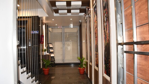 A hallway with a modern design, featuring a metal gate, potted plants, and a patterned wall. - Hotel Rize Inn (Bengaluru)