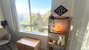 Ein Zimmer mit einem großen Fenster, einer hölzernen Bank, einem Regal mit einem Teddybären und einem Schild mit der Aufschrift 'The Critical Tcss Slide Society'.