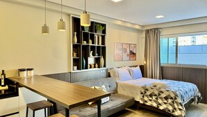Habitació d'hotel moderna amb un llit, un sofà, una taula de fusta i una biblioteca de paret.