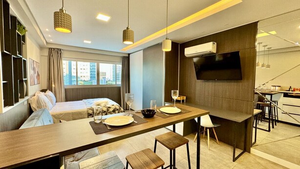 Una habitació d'hotel moderna amb un llit, una zona de menjador i un televisor penjat a la paret.