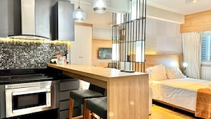Una cucina moderna con forno a microonde integrato, un'isola in legno e sgabelli da bar neri.