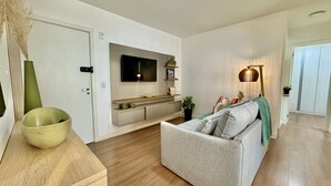 Un salon moderne avec un canapé, un téléviseur fixé au-dessus d’une console en bois et un lampadaire.