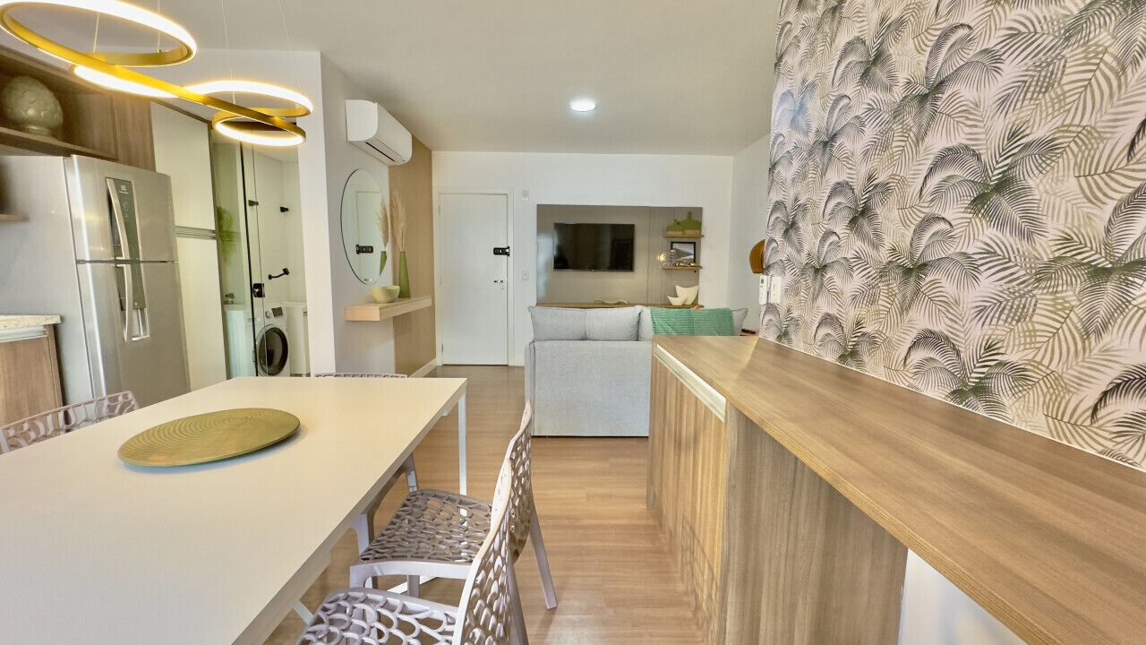 A modern kitchen with a built-in refrigerator, a dining area with a white table, and a patterned wall.