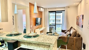 Eine moderne Küche mit Granit-Arbeitsplatten, einem Essbereich mit einer Couch und Stühlen sowie einem an der Wand montierten Fernseher.
