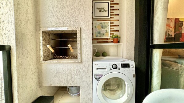 Un espace buanderie comprenant un lave-linge, un étendoir et une étagère avec des objets décoratifs.
