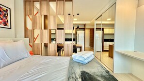 A modern hotel room with a bed, a desk, and a kitchenette. - Incrível Studio com Lava Seca e vaga no Lifespace (Curitiba)