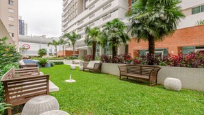 A well-maintained outdoor area with a grassy lawn, wooden benches, and potted plants.