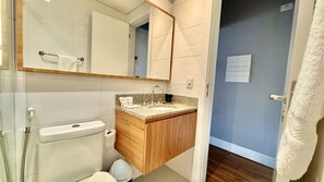 A bathroom with a toilet, sink, mirror, and towel rack.
