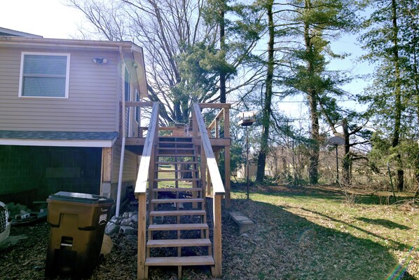 A wooden staircase leading to a deck area of a house surrounded by trees. - The Boho Roost (Bloomington)