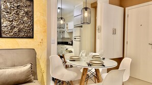 A dining area with a round table set for four, white chairs, and hanging pendant lights. - Studio Bem Planejado, frente ao Shopping Curitiba (Curitiba)