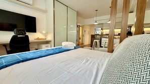 A hotel room with a bed, a desk, a TV, and a kitchenette. - Studio Luxo na frente do Shopping Curitiba, c/vaga (Curitiba)