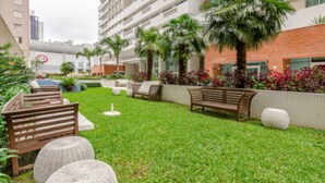 A well-maintained outdoor area with a grassy lawn, wooden benches, and potted plants.