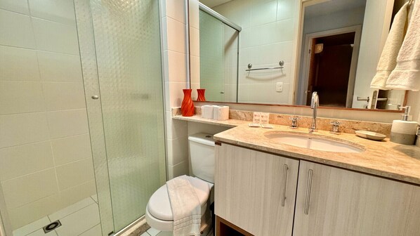 Une salle de bain équipée d’une douche, de toilettes, d’un lavabo et d’un miroir.