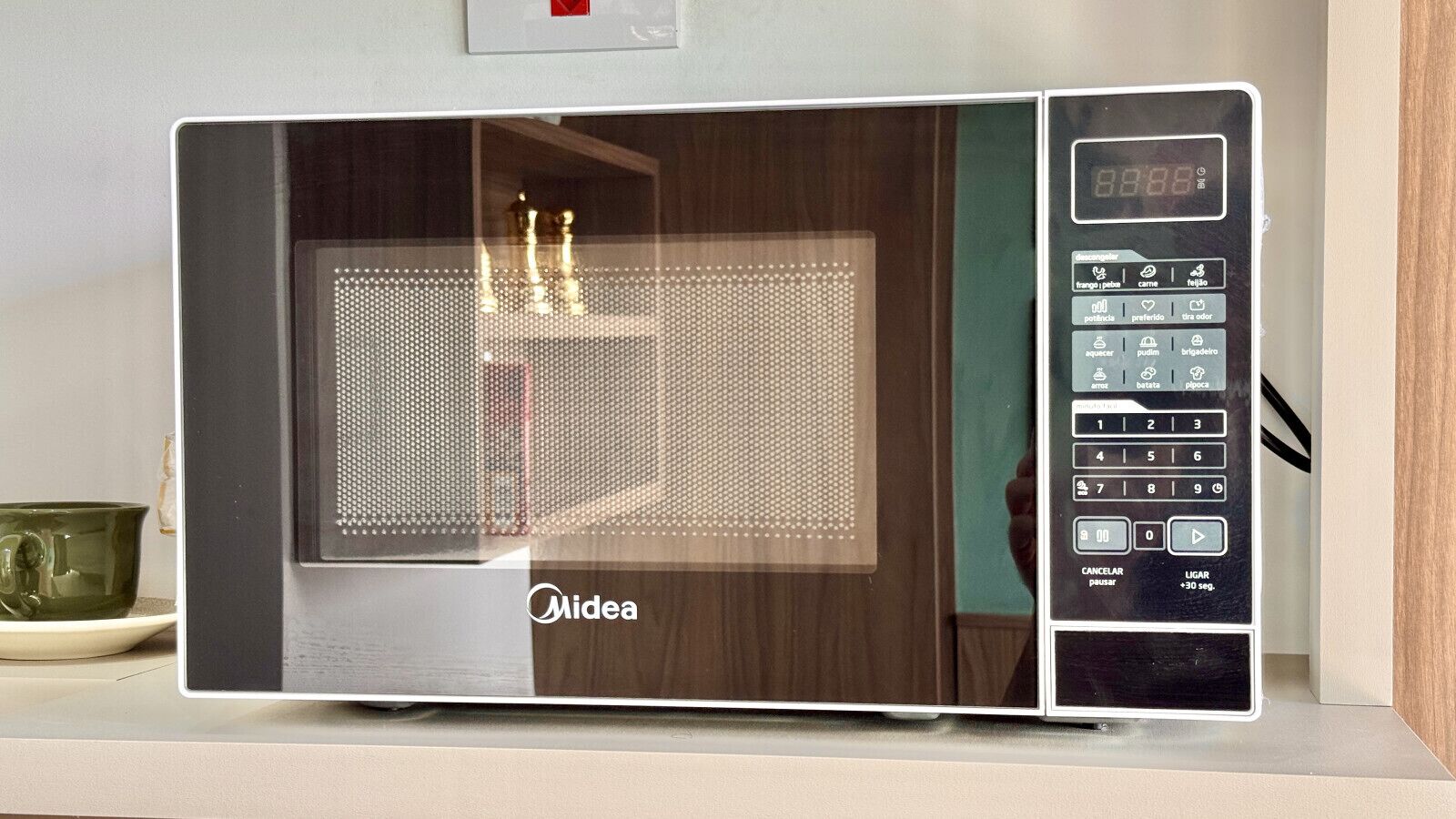 Un four à micro-ondes doté d’un écran numérique et d’un panneau de commande, posé sur un plan de travail de cuisine.