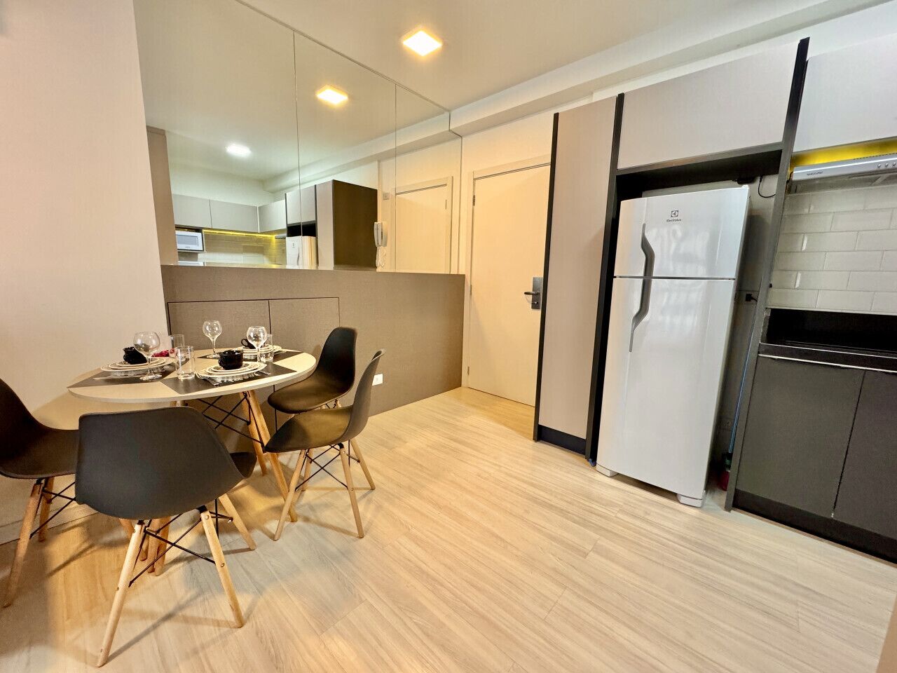 Une cuisine moderne avec un coin repas, comprenant une table ronde avec des chaises, un réfrigérateur et un four à micro-ondes.