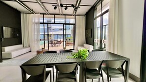 A modern conference room with a large table, chairs, and a view of the outdoor seating area.
