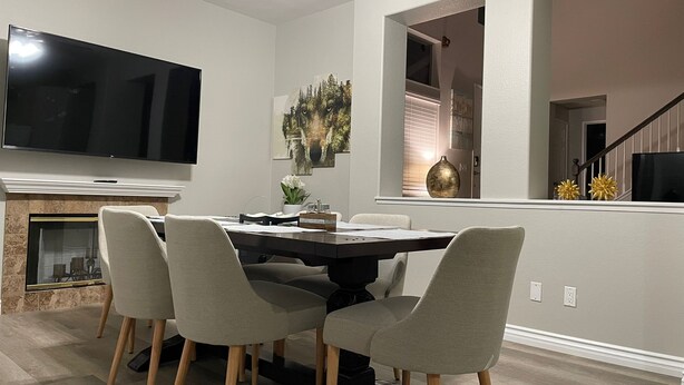 Un espace repas moderne doté d’un grand téléviseur à écran plat, d’une cheminée et d’une table à manger avec quatre chaises.