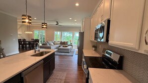 A modern kitchen with a central island, stainless steel appliances, and a dining area with a sofa and chairs.