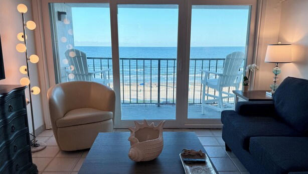 Habitación con vista al mar, un sofá, una silla, un aparador y una mesa con un adorno.