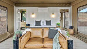 Une chambre spacieuse avec un grand lit, deux tables de chevet, un canapé et une fenêtre donnant sur l’extérieur.