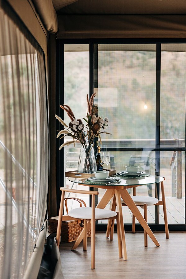 A dining area with a glass table, wooden chairs, and a vase with dried plants. - Jarabin (Berremangra)