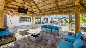 A covered outdoor area with a thatched roof, wicker furniture, and an American flag. - Dream Gateway, Luxury, Exclusive (Bradenton)