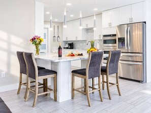 Une cuisine moderne avec un îlot central, des appareils en acier inoxydable et des chaises en bois.