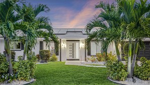 A modern house with a well-maintained lawn, two palm trees, and a front door with a glass panel. - Dream Gateway, Luxury, Exclusive (Bradenton)