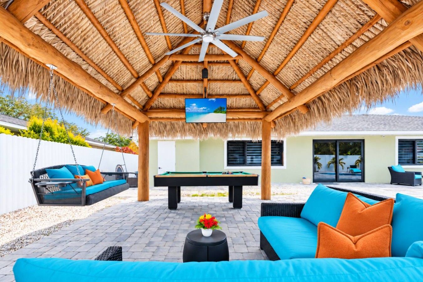 A covered outdoor area with a pool table, a swing chair, and a sofa.