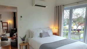 A bedroom with a bed, bedside lamp, and a view of the outdoors.