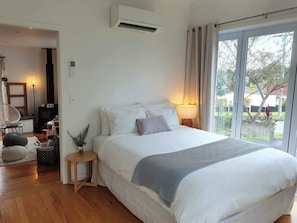 Un dormitorio con cama, lámpara de noche y vistas al exterior.