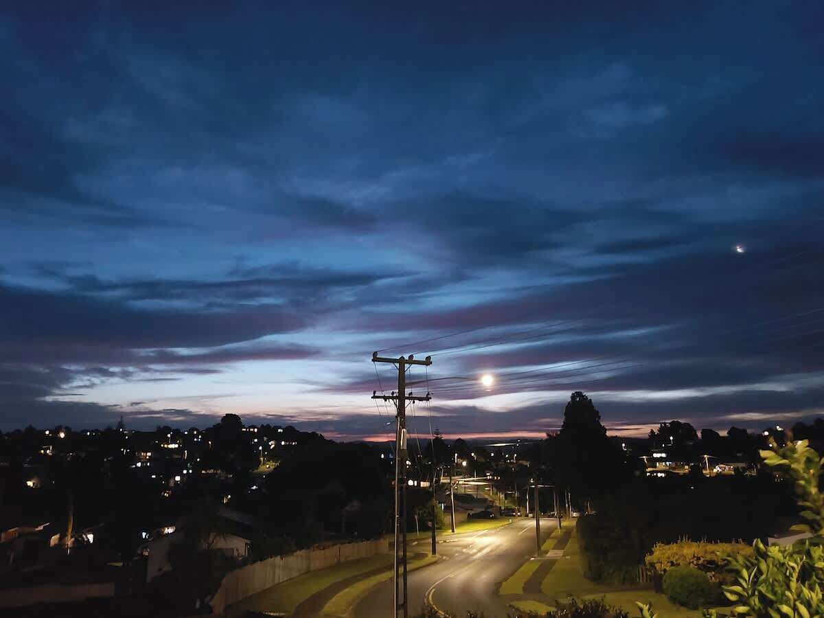 A nighttime view of a residential area with houses, a street, and a utility pole.