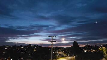 A nighttime view of a residential area with houses, a street, and a utility pole.