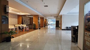 Un hall espacioso con mostrador de recepción, zona de estar y un amplio ventanal con vistas al exterior.
