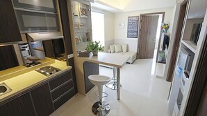 Una cocina moderna con una isla central, un comedor con una mesa y sillas blancas, y una sala de estar con un sofá y un reloj en la pared.