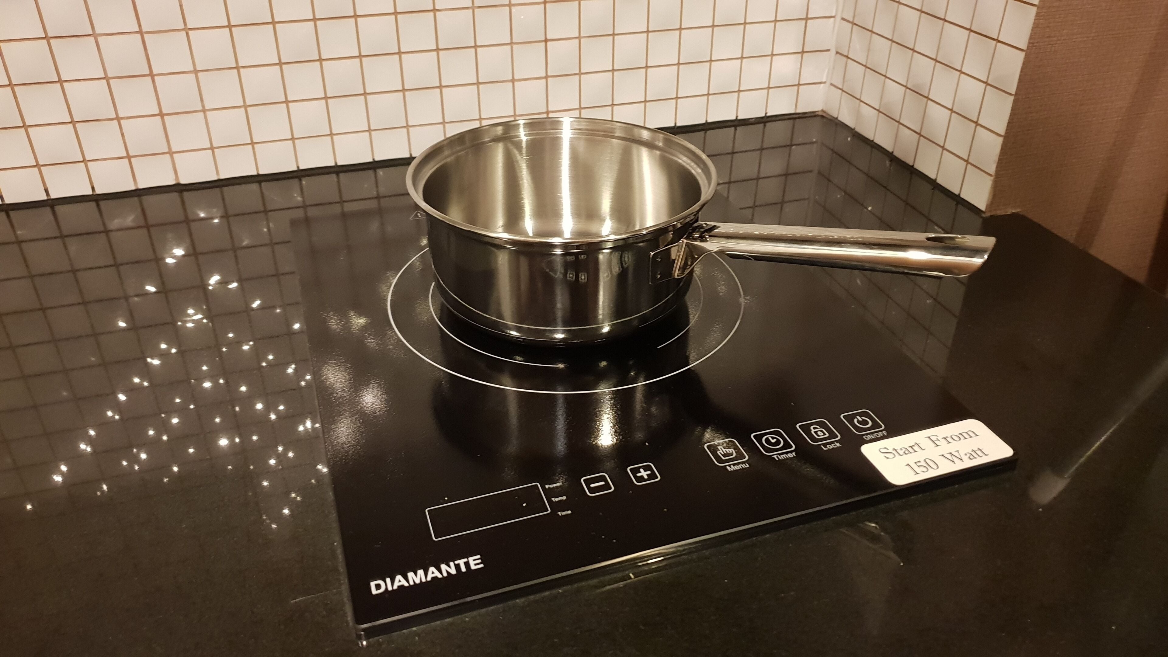 A black induction cooktop with a stainless steel pot on it.