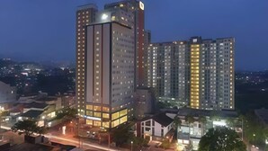 Un hotel moderno de gran altura con varios pisos, una entrada destacada y una fachada bien iluminada.
