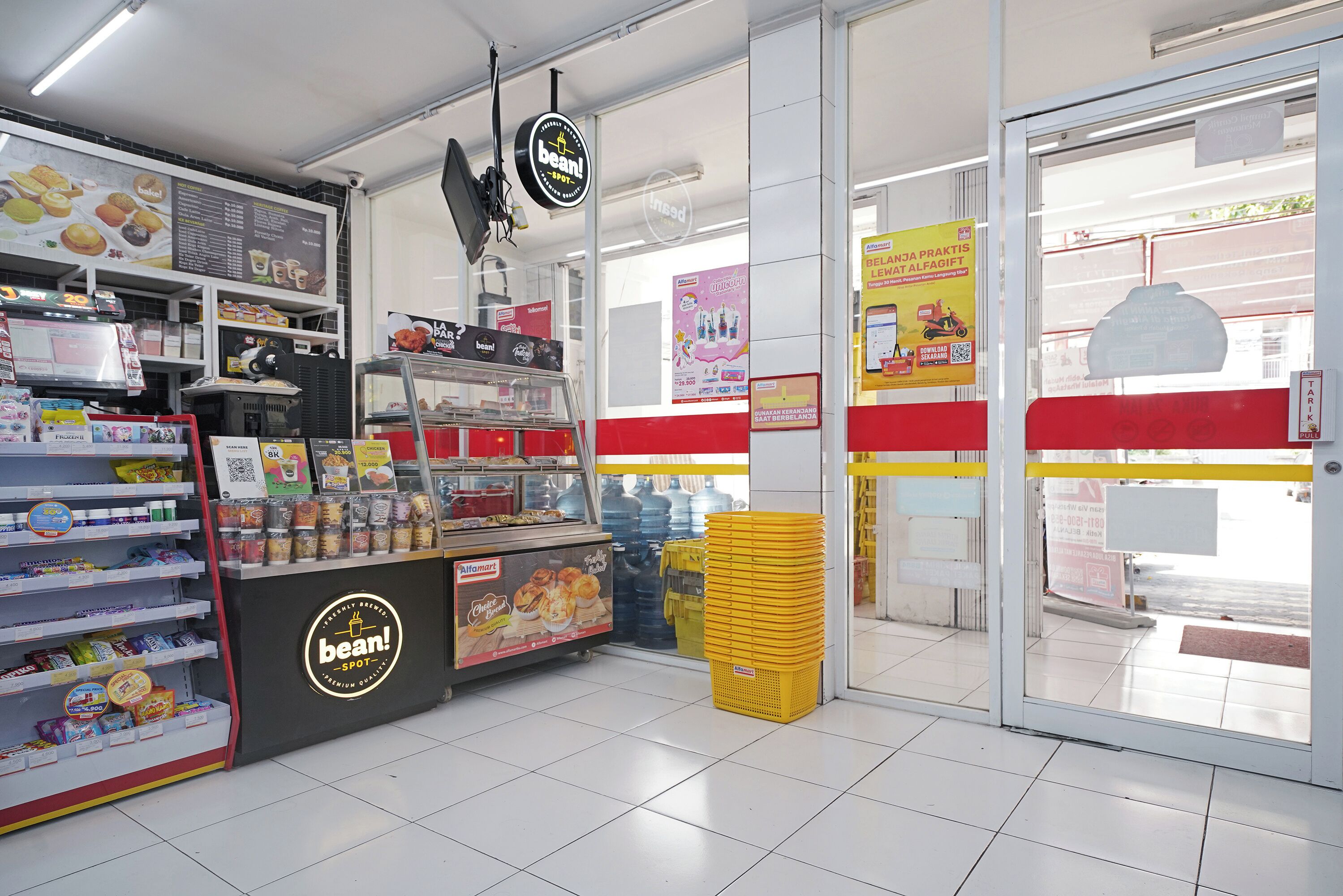Un comptoir de boulangerie où sont exposés divers produits de boulangerie, ainsi qu’une pile de paniers jaunes.