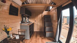 Un interior de madera con cocina, comedor y un amplio ventanal corredera a un espacio exterior.
